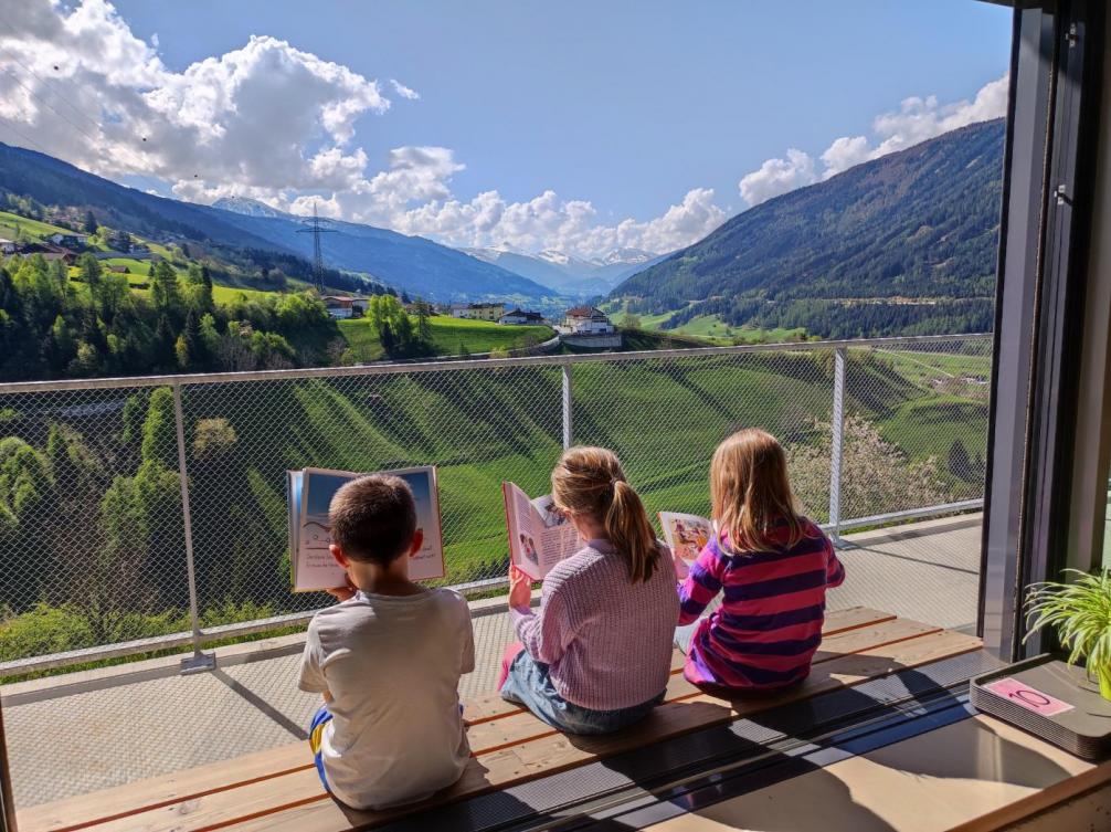 Ausblick richtung Matrei, Kinder beim Lesen auf der Terrasse